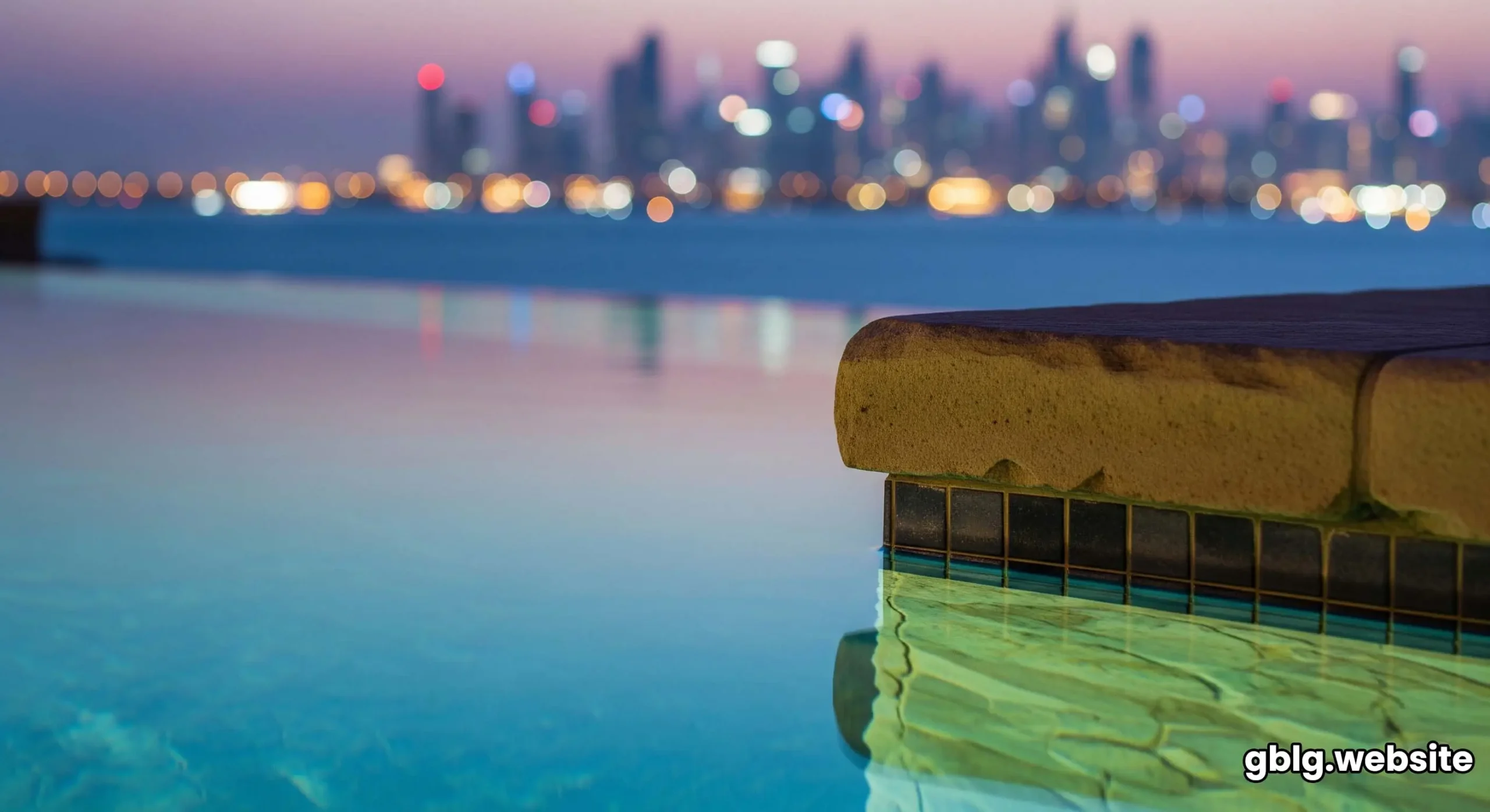 A stunning view from a villa terrace at sunset, with a glowing infinity pool that seems to blend into the sea and the Dubai skyline.